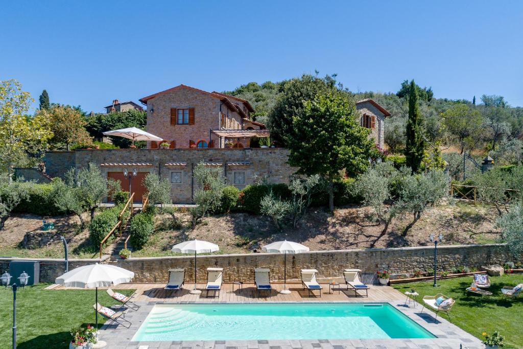 - une piscine avec des chaises et des parasols en face d'une maison dans l'établissement Corte della Luna, à Cortone