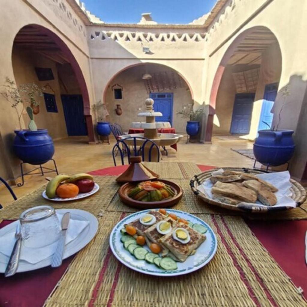 une table avec plusieurs assiettes de nourriture dessus dans l'établissement Hôtel Riad Tadarte Familier, à Merzouga
