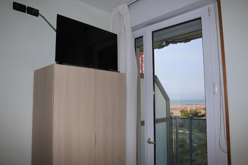 un salon avec une télévision à écran plat et une fenêtre dans l'établissement Hotel La Bussola, à Lido di Jesolo