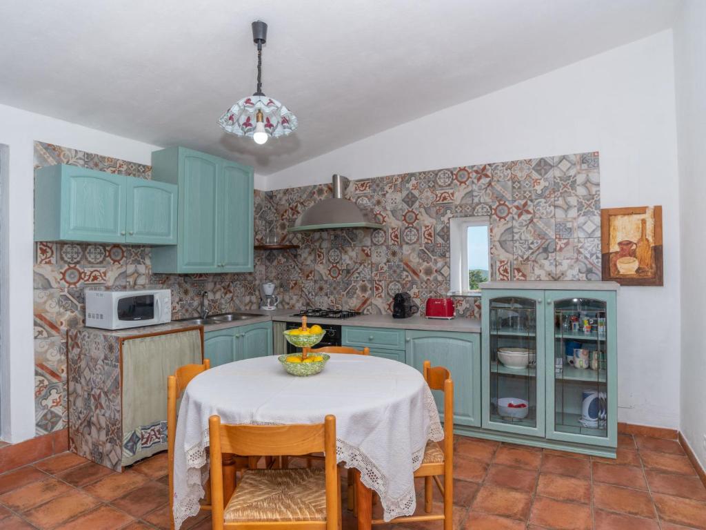 une cuisine avec des placards bleus et une table avec des chaises dans l'établissement Villa Scalitti by Interhome, à Trinità d'Agultu e Vignola 31 autres photos