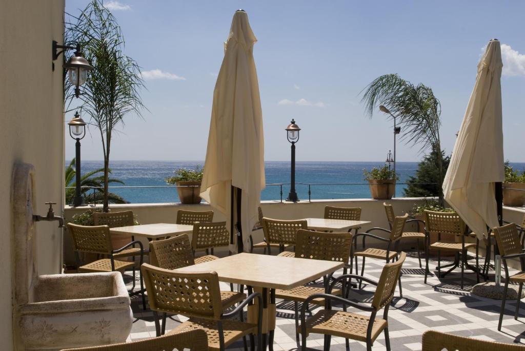 une terrasse extérieure avec des tables et des parasols blancs dans l'établissement Palazzo Reginella, à Bovalino Marina