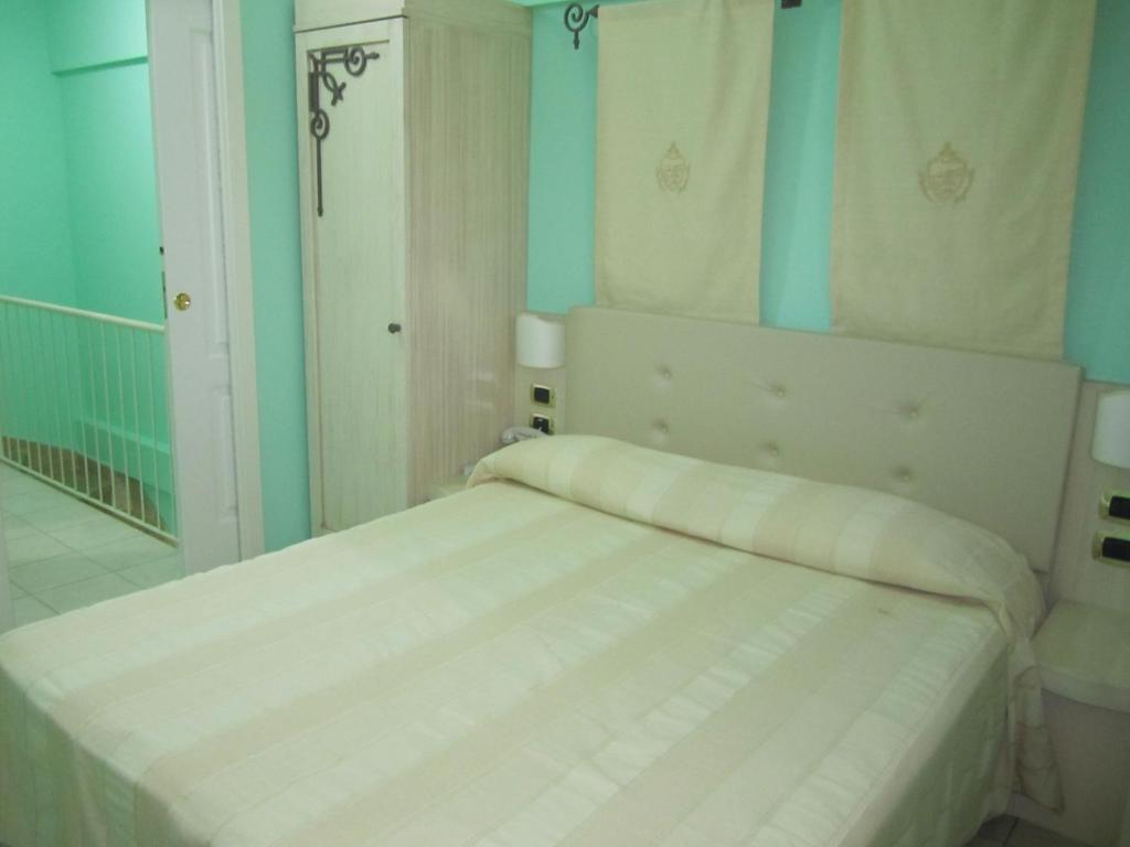 un lit blanc dans une chambre aux murs bleus dans l'établissement Palazzo Reginella, à Bovalino Marina