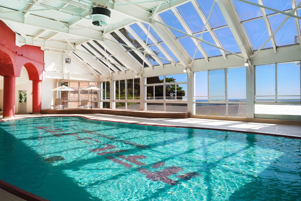 une piscine intérieure avec un grand plafond en verre dans l'établissement Hotel New Akao, à Atami
