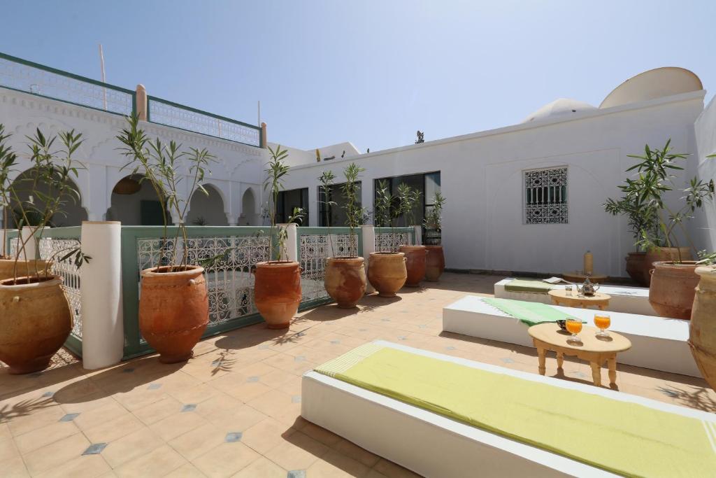 une cour avec des plantes en pot et des tables dans un bâtiment dans l'établissement RIAD DAR DAR, à Marrakech
