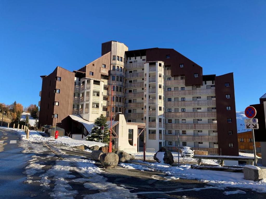 un grand immeuble avec de la neige devant lui dans l'établissement Appartement 5 pers Résidence Les Mélèzes quartier les Bergers Alpe d Huez, à L'Alpe-d'Huez