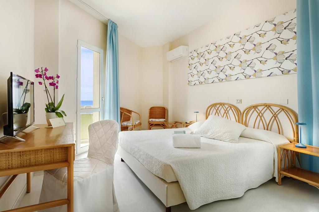 une chambre avec un lit, une table et un bureau dans l'établissement Hotel Mida, à Scoglitti