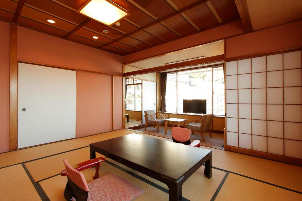 Il comprend un salon avec une table et des chaises ainsi qu'une chambre dotée d'une télévision. dans l'établissement Atagawa Yamatokan, à Higashiizu