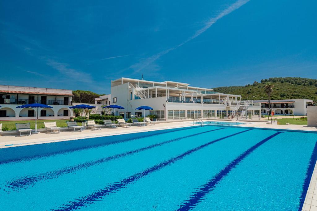 une grande piscine devant un immeuble dans l'établissement Hotel Portoconte, à Porto Conte