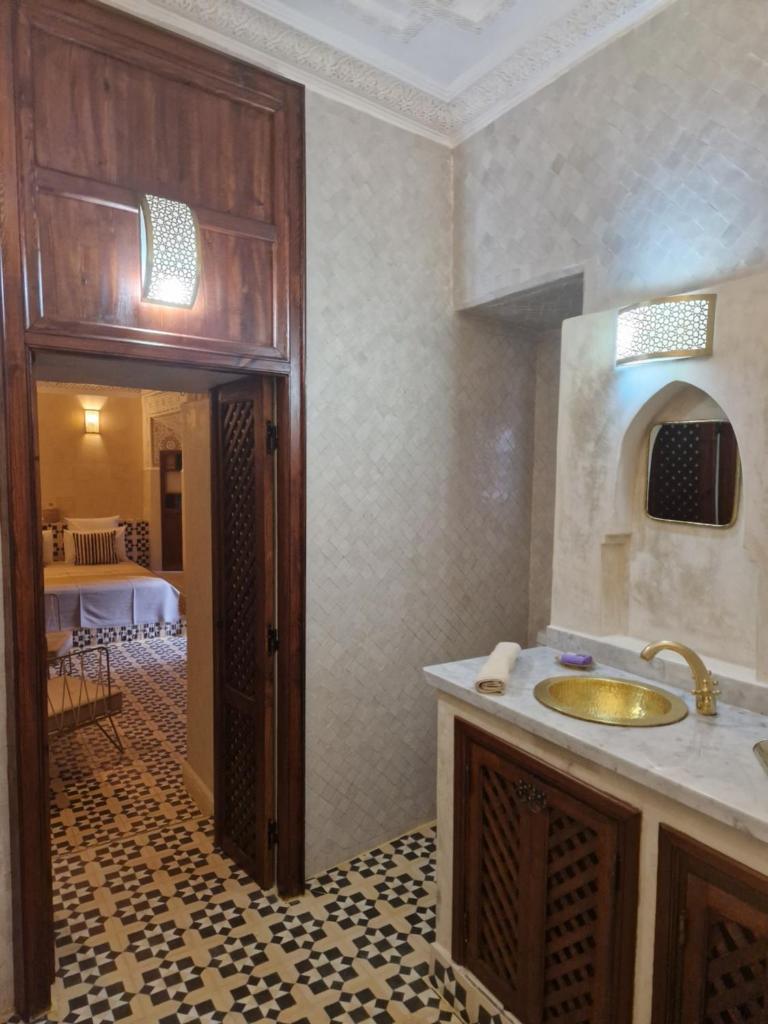 une salle de bain avec un lavabo et une pièce avec une table dans l'établissement Riad Les Nuits de Marrakech, à Marrakech