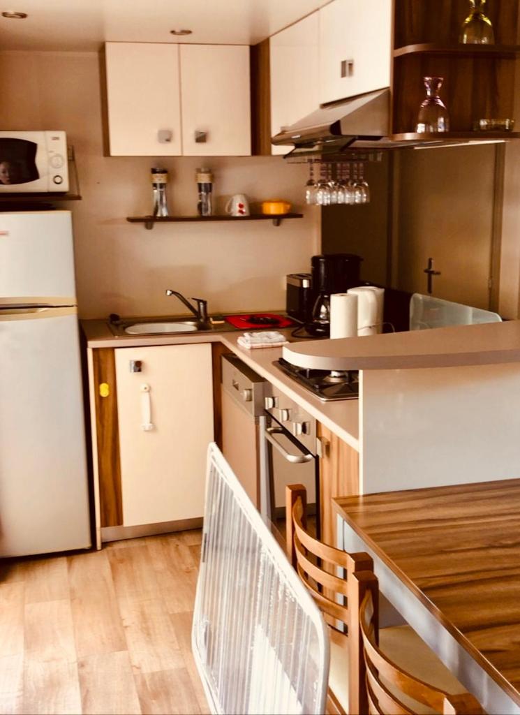 - une cuisine avec des appareils blancs, une table et des chaises dans l'établissement Les Pierres Couchées 4 étoiles à St Brévin les Pins emplacement BR22 3CH 2SDB 8 personnes, à Saint-Brévin-les-Pins