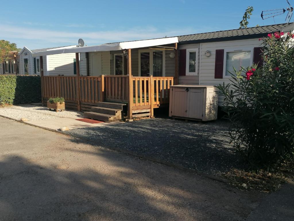 une maison avec un porche et une clôture dans l'établissement MOBILHOME COSY SPACIEUX 42m2, CLIMATISE, TV & LL, 3 chambres, à Vic-la-Gardiole