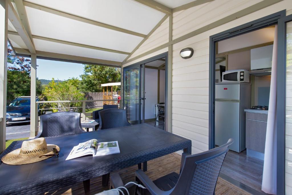 un patio avec une table et des chaises et une cuisine dans l'établissement Camping Paradis La Pinede, à Gréoux-les-Bains
