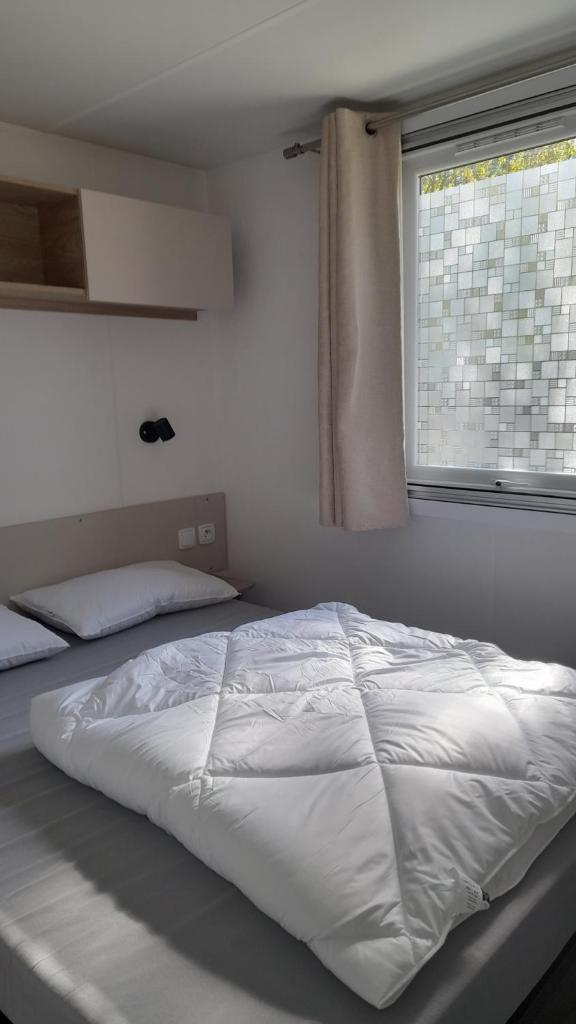 - un lit blanc dans une chambre avec fenêtre dans l'établissement Le Bois Dormant, à Saint-Jean-de-Monts