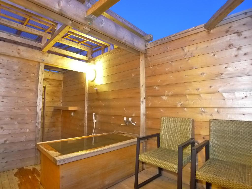- un sauna avec 2 chaises et une baignoire dans l'établissement Hotel Shin Makomo, à Itako