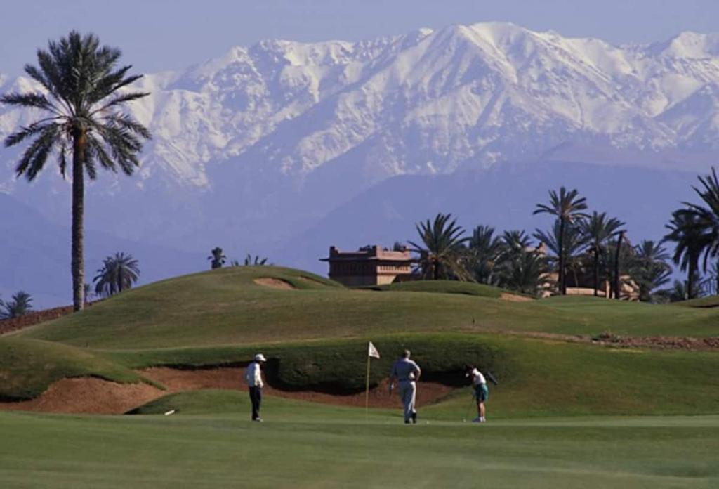 3 personnes sur un parcours de golf avec une montagne en arrière-plan dans l'établissement Riad Dar Rania Marrakech Médina Jemaa El Fna, à Marrakech