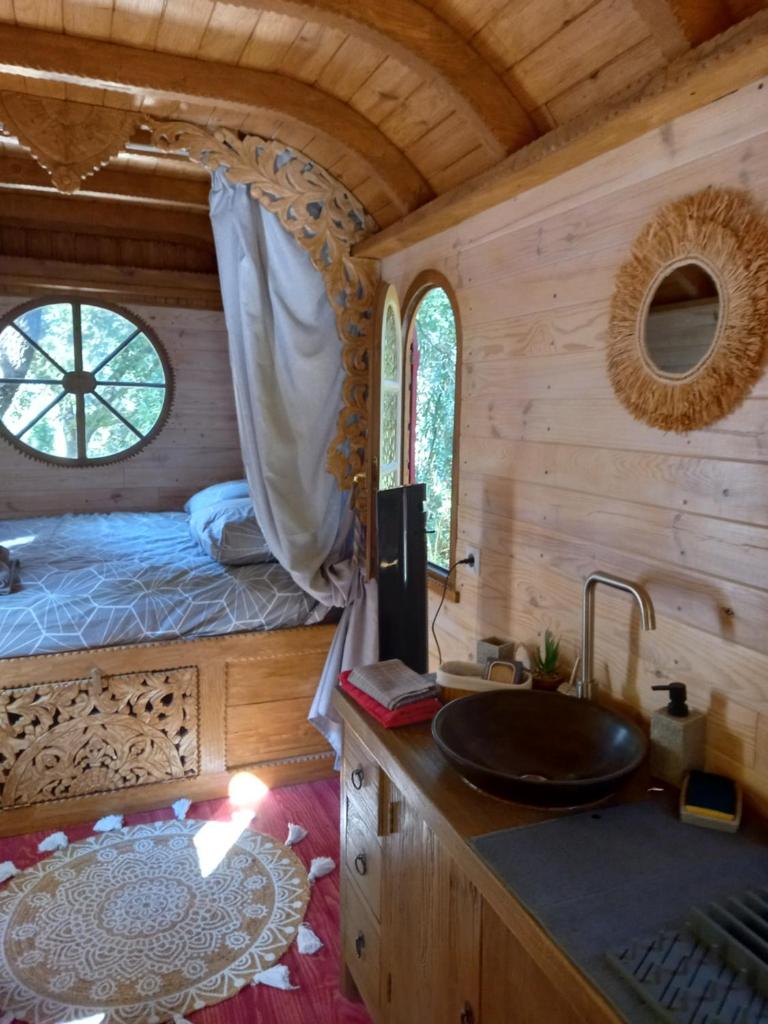 une salle de bain avec un lavabo et une chambre avec un lit dans l'établissement La roulotte du petit paradis, à Saint-Rémy-de-Provence