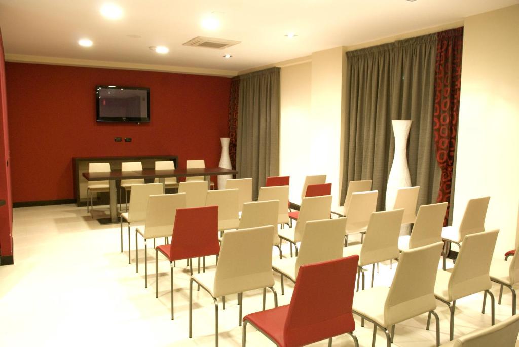une salle de conférence avec des chaises blanches et une télévision dans l'établissement La Isla Resort, à Pontecagnano