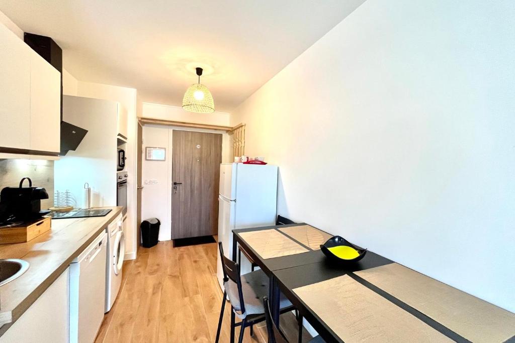 une cuisine avec une table et un réfrigérateur blanc dans l'établissement Comfortable studio well located in Saint-Gervais, à Saint-Gervais-les-Bains