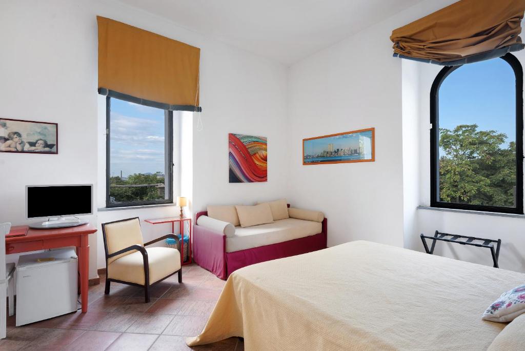une chambre avec un lit, un bureau et une télévision dans l'établissement Flegrea House, à Pouzzoles