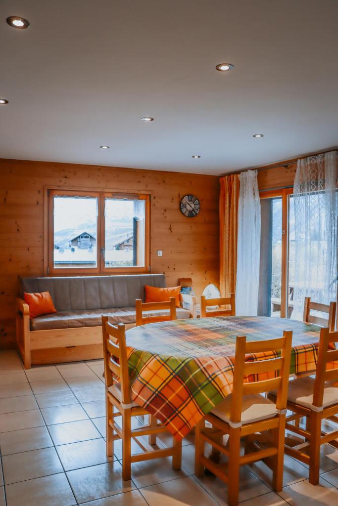 une salle à manger avec une table, des chaises et un canapé dans l'établissement Chalet Les Hellebores, à La Toussuire