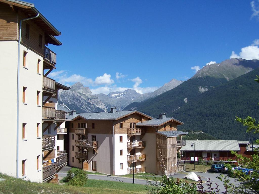 un groupe de bâtiments avec des montagnes en arrière-plan dans l'établissement Résidence Goélia Les Flocons d'Argent, à Aussois