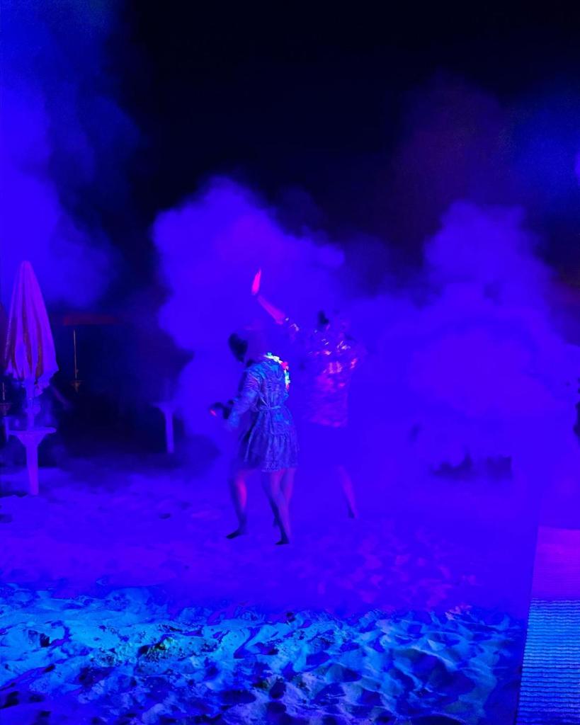 une femme en robe dansant sur la plage la nuit dans l'établissement Hotel Holiday, à Martinsicuro