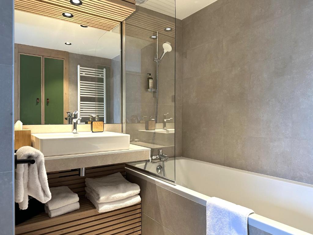 une salle de bain avec un lavabo, une baignoire et un miroir dans l'établissement La Cachette, Friendly Hotel & Spa, à Arc 1600 37 autres photos