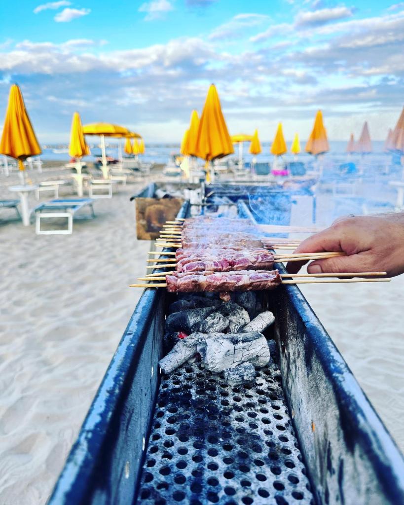 une personne tenant une table avec de la nourriture sur la plage dans l'établissement Hotel Holiday, à Martinsicuro