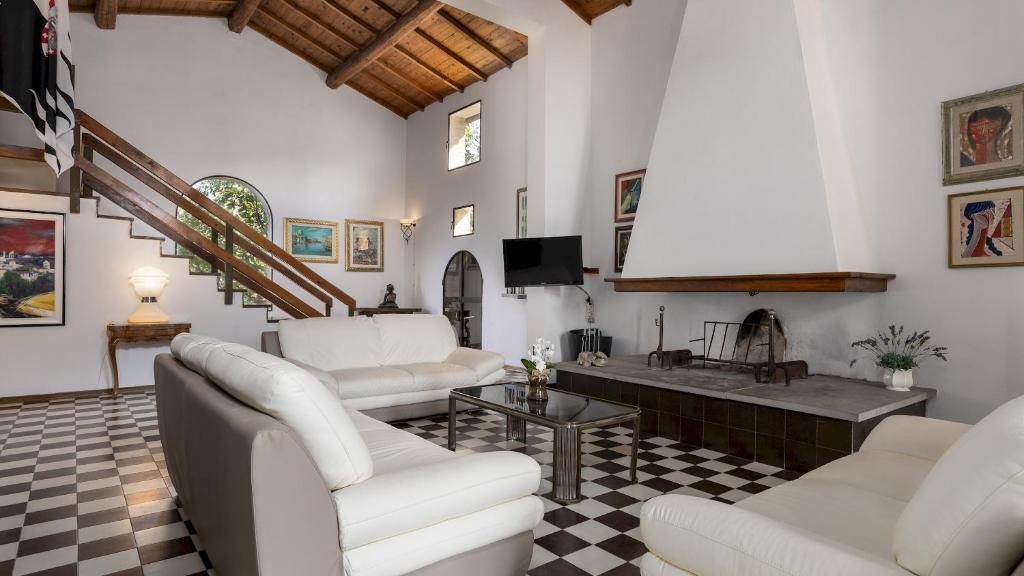 Il comprend un salon doté d'un mobilier blanc et d'une télévision. dans l'établissement VILLA BEL PANORAMA 8, Emma Villas, à San Gimignano