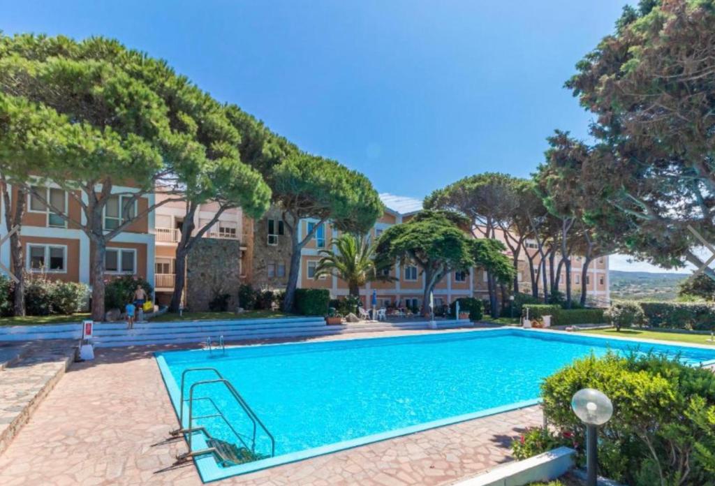 une piscine devant une maison avec des arbres dans l'établissement Recidence gallo di Gallura Casa Azzurra, à Santa Teresa Gallura