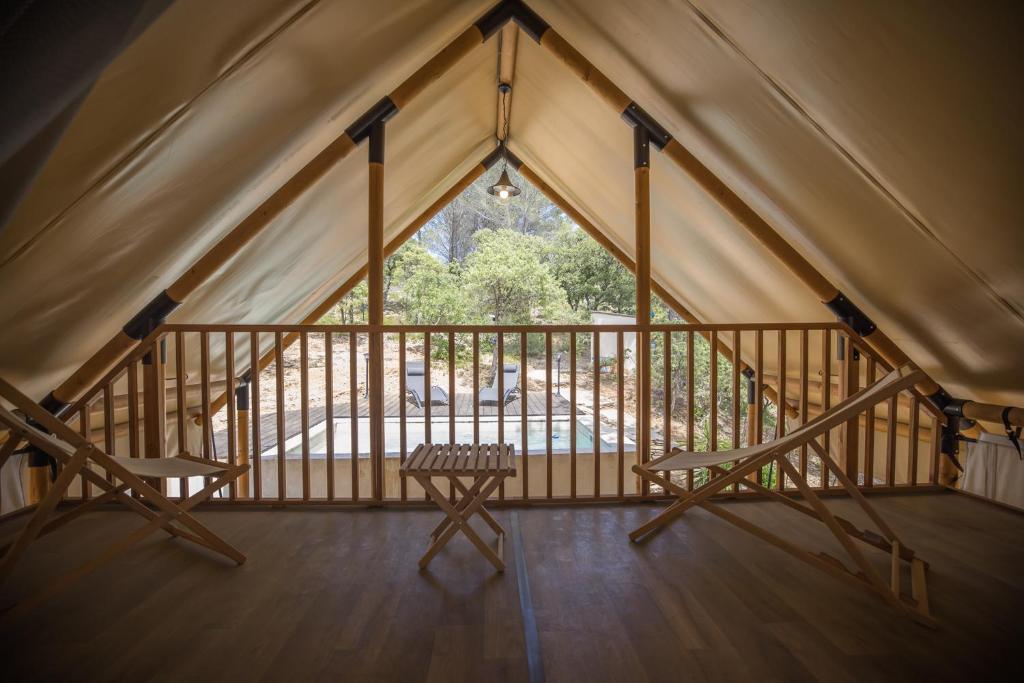 une chambre avec deux chaises et une fenêtre dans une tente dans l'établissement Le lodge de la Catouniere, à Castillon-du-Gard