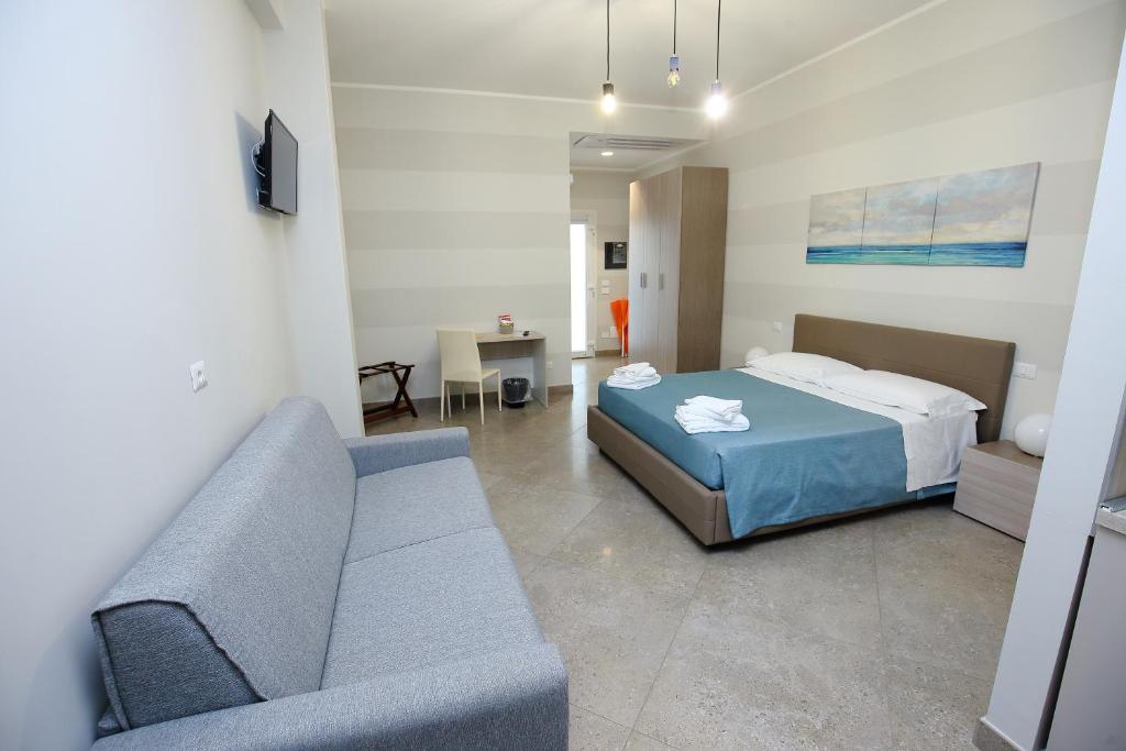 une chambre avec un lit et un canapé dans une pièce dans l'établissement Sand Hotel, à Botricello