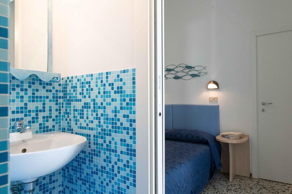 La salle de bains est pourvue d'un lavabo et d'un mur carrelé bleu. dans l'établissement Hotel Smart Cervia B&B, à Cervia