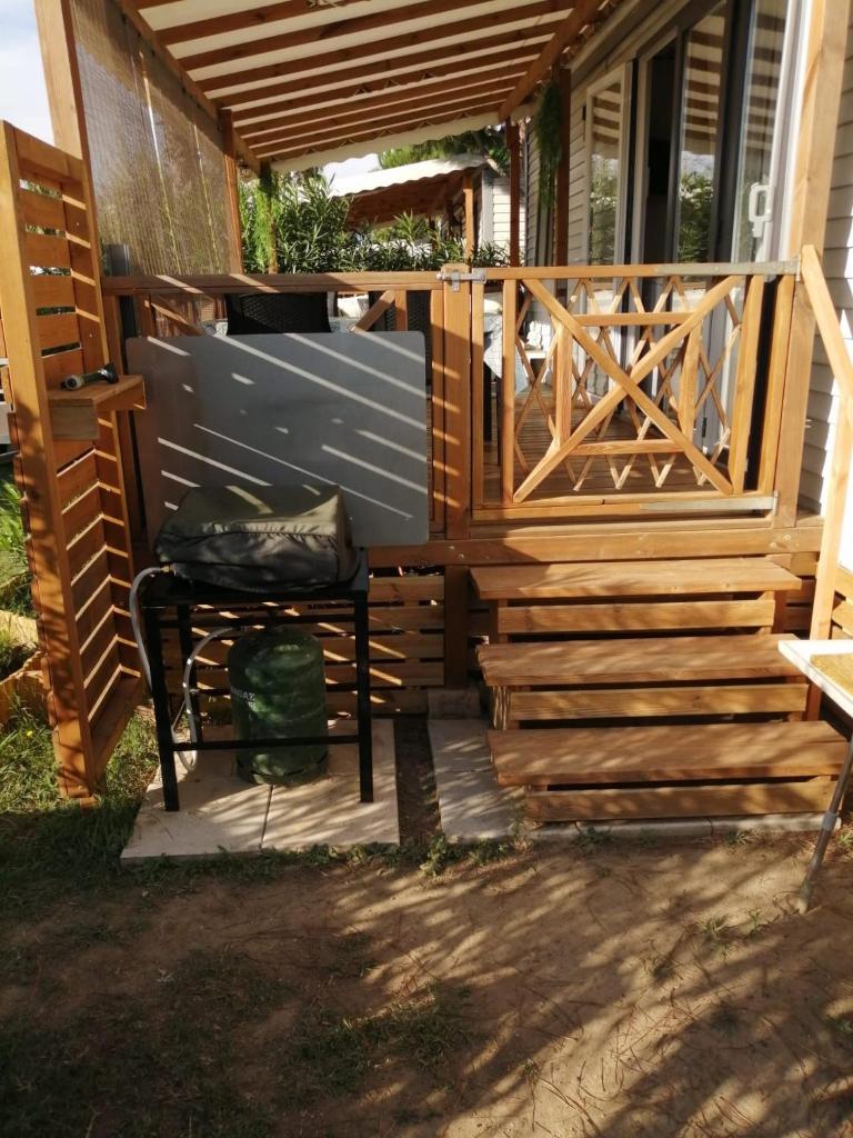 une terrasse en bois avec une chaise sur une terrasse couverte dans l'établissement Camping Del Mar B07, Mobil home O'Hara résidentiel, 4 personnes, Camping Del Mar Village, à Argelès-sur-Mer
