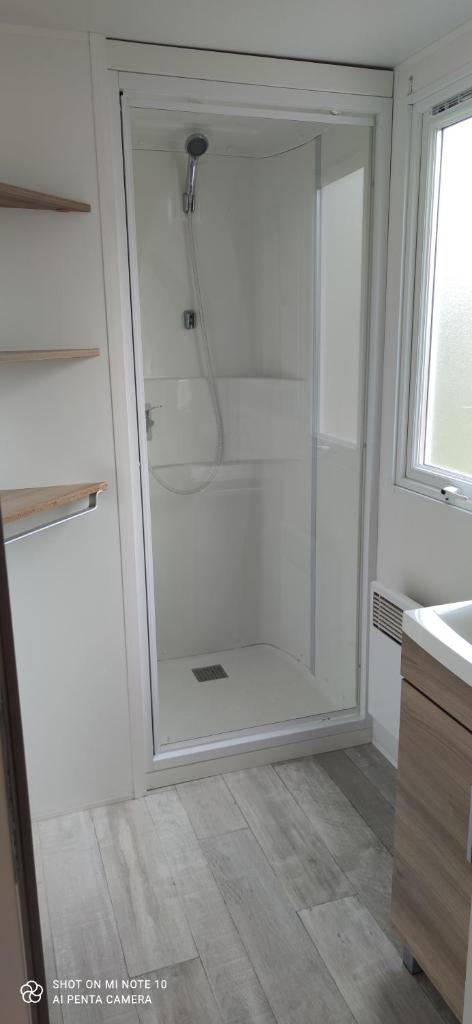 une douche avec une porte vitrée dans une salle de bain dans l'établissement Domaine de karlann 4Etoiles Mobil-home, à Pont-Aven