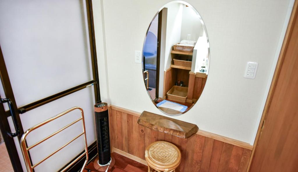un miroir dans une petite pièce avec une chaise dans l'établissement Kamegawa Onsen HATAGO Yuyu, à Beppu