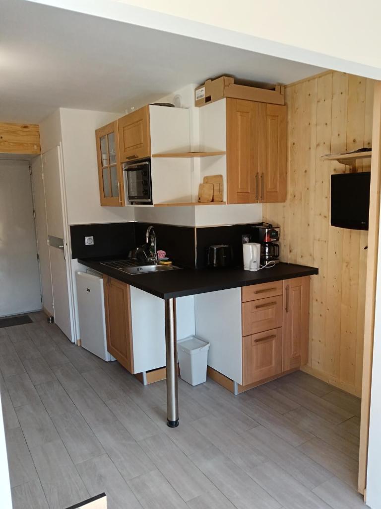une cuisine avec des armoires en bois et un comptoir noir dans l'établissement Appartement plein sud, Val Thorens Centre, à Val Thorens