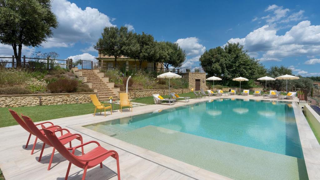 une piscine avec chaises longues et parasols dans l'établissement CASOLARE SAN MARTINO 16&1, Emma Villas, à Pomarance