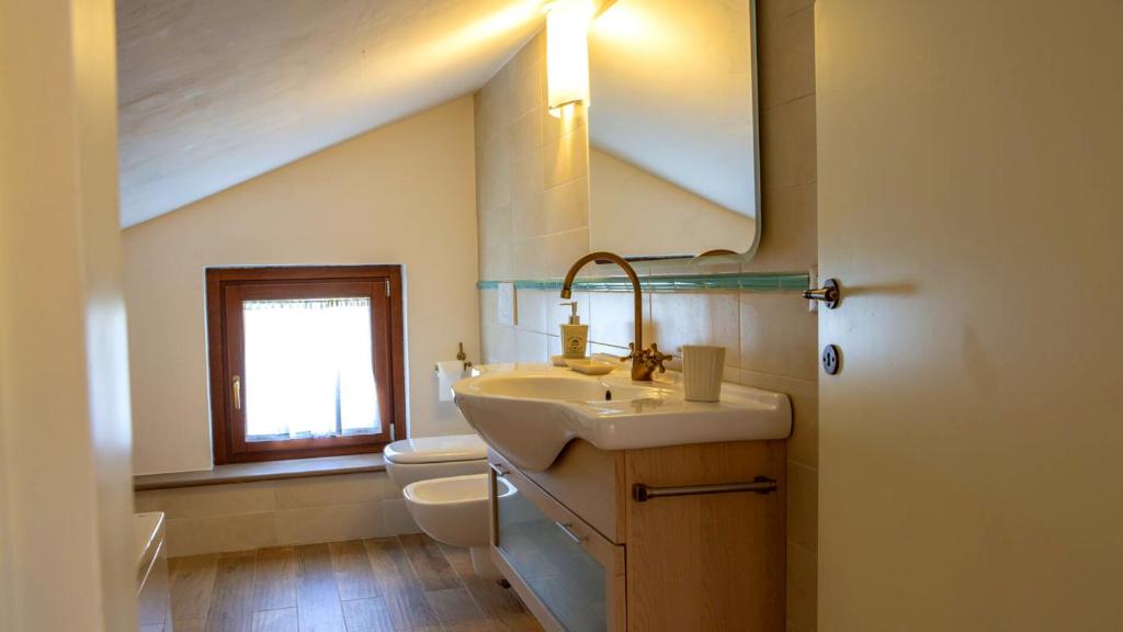 une salle de bain avec un lavabo, des toilettes et un miroir dans l'établissement Villa Domus - Homelike Villas, à Montegiorgio