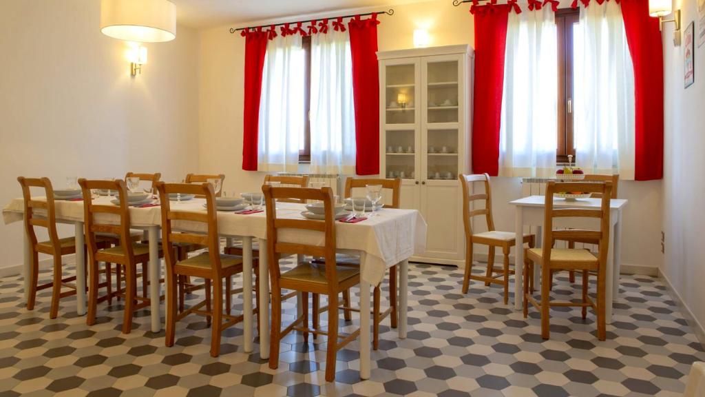 - une salle à manger avec une table, des chaises et des rideaux rouges dans l'établissement Villa Domus - Homelike Villas, à Montegiorgio