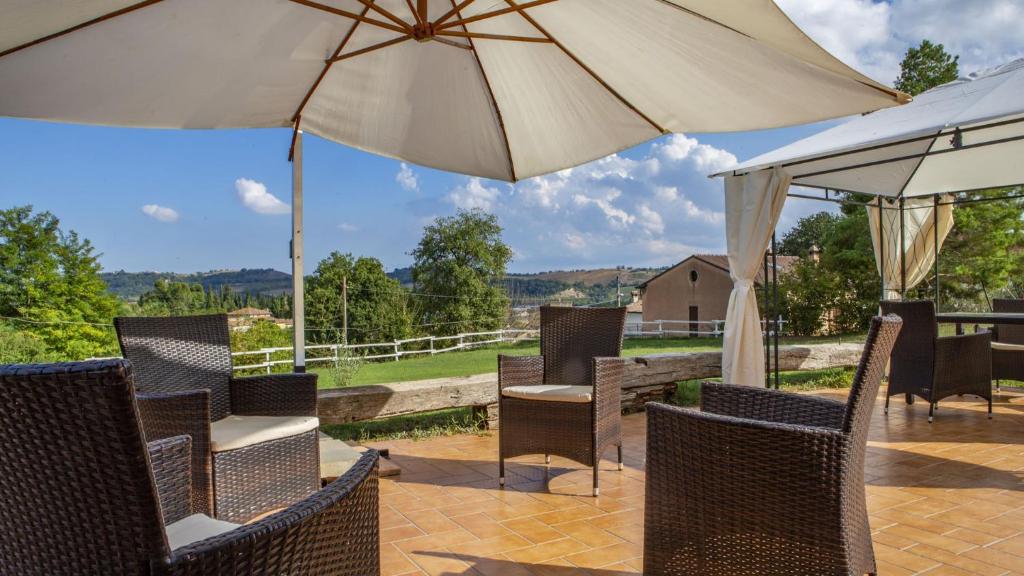 une terrasse avec des chaises et un parasol dans l'établissement Villa Domus - Homelike Villas, à Montegiorgio