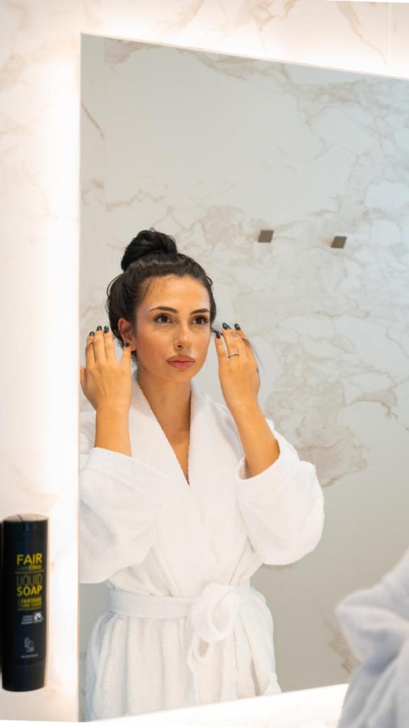 une femme en robe blanche debout devant un miroir dans l'établissement POPULA - The Lifestyle Hotel, à Gallipoli