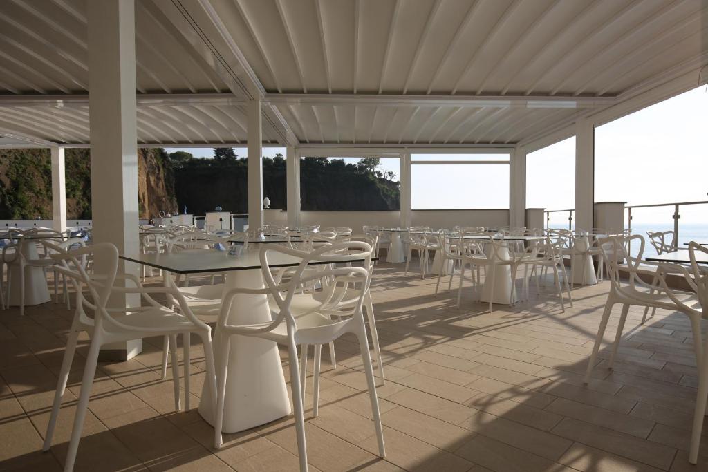 une rangée de tables et de chaises blanches sur une terrasse dans l'établissement Hotel Giosue' a mare Sorrento, à Meta