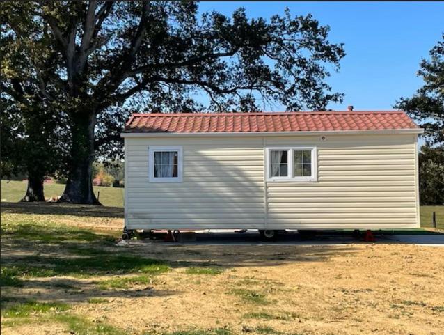 un petit hangar blanc avec un toit rouge dans un champ dans l'établissement TINY HOUSE, à Souvans