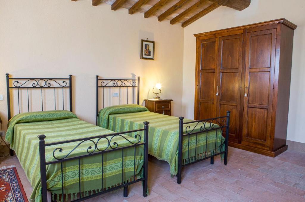 une chambre avec deux lits et une armoire en bois dans l'établissement Villa Orizzonte - Homelike Villas, à Todi
