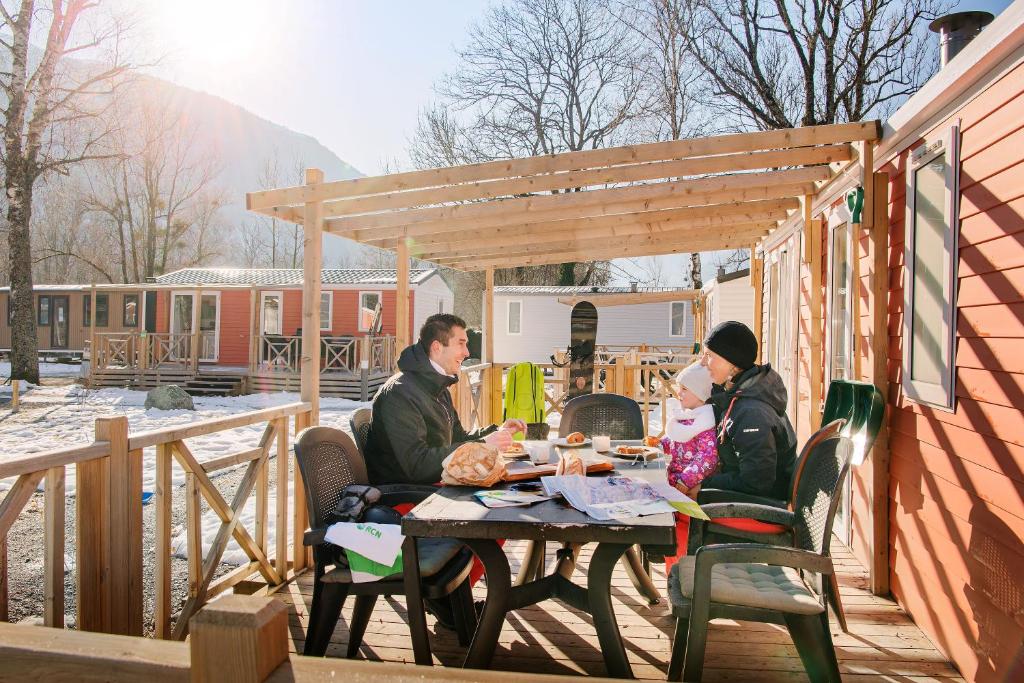 deux personnes assises à une table sur une terrasse dans l'établissement Camping RCN Belledonne, au Bourg-dʼOisans
