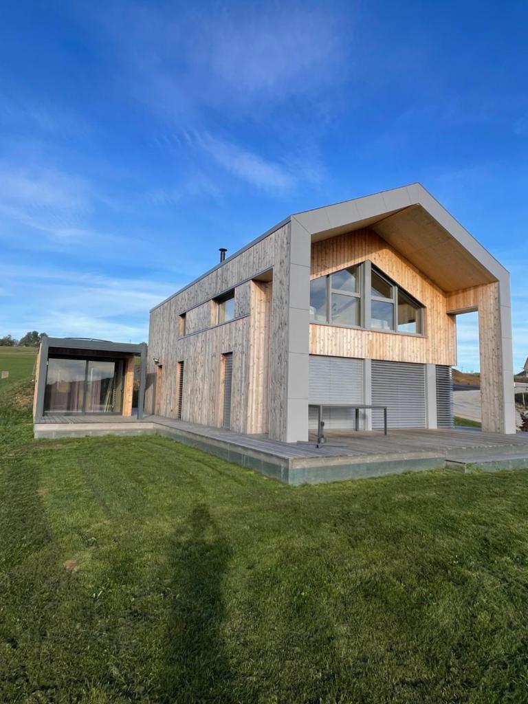 une maison moderne avec une pelouse verte en face de celle-ci dans l'établissement Magnifique villa nature le Bois d'Aura, à Luisans