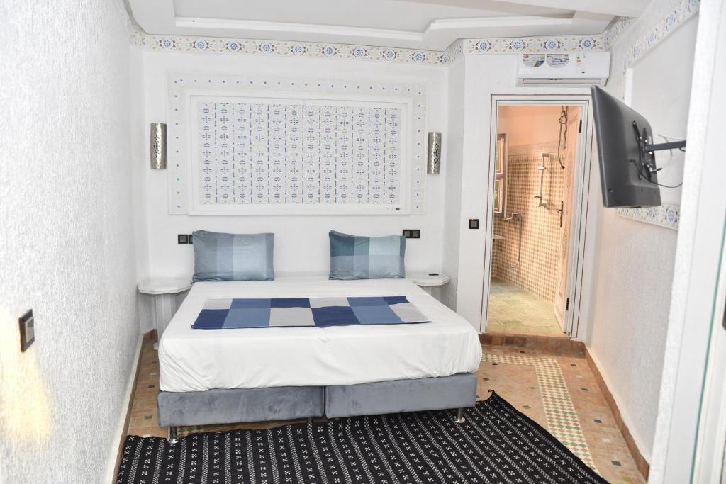 - une petite chambre avec un lit et une télévision dans l'établissement Riad golf stinia, à Meknès