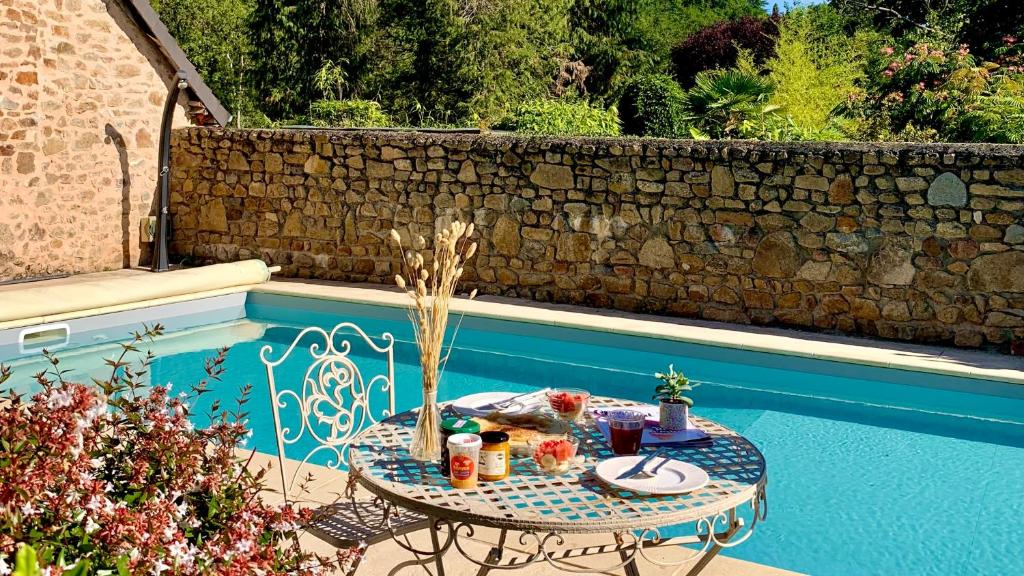 une table avec de la nourriture dessus à côté d'une piscine dans l'établissement Gîte La Cassine Saint-Ceneri-le-Gerei, à Moulins-le-Carbonnel 9 autres photos