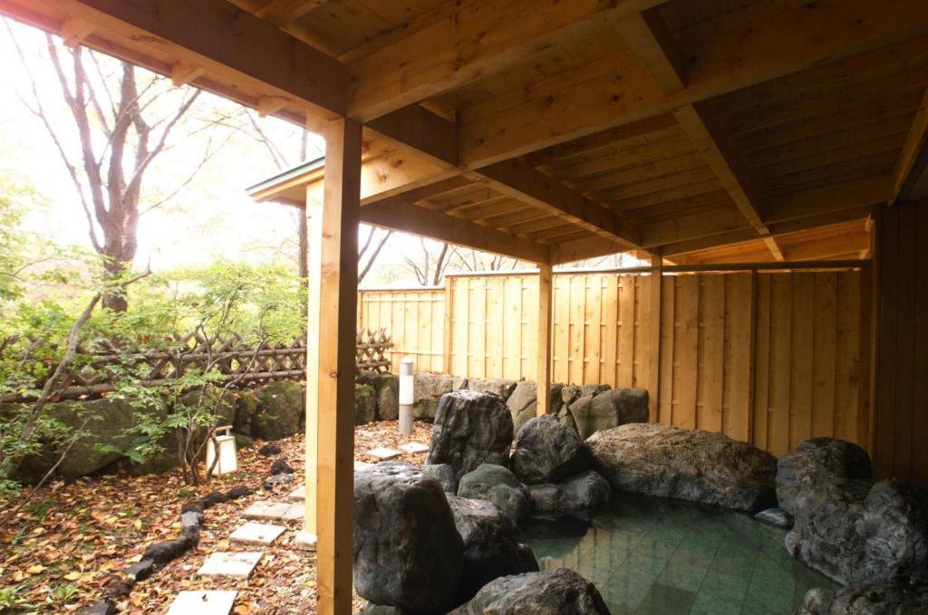 - un pavillon en bois avec des rochers dans une cour dans l'établissement Shikotsuko Daiichi Hotel Suizantei, à Chitose